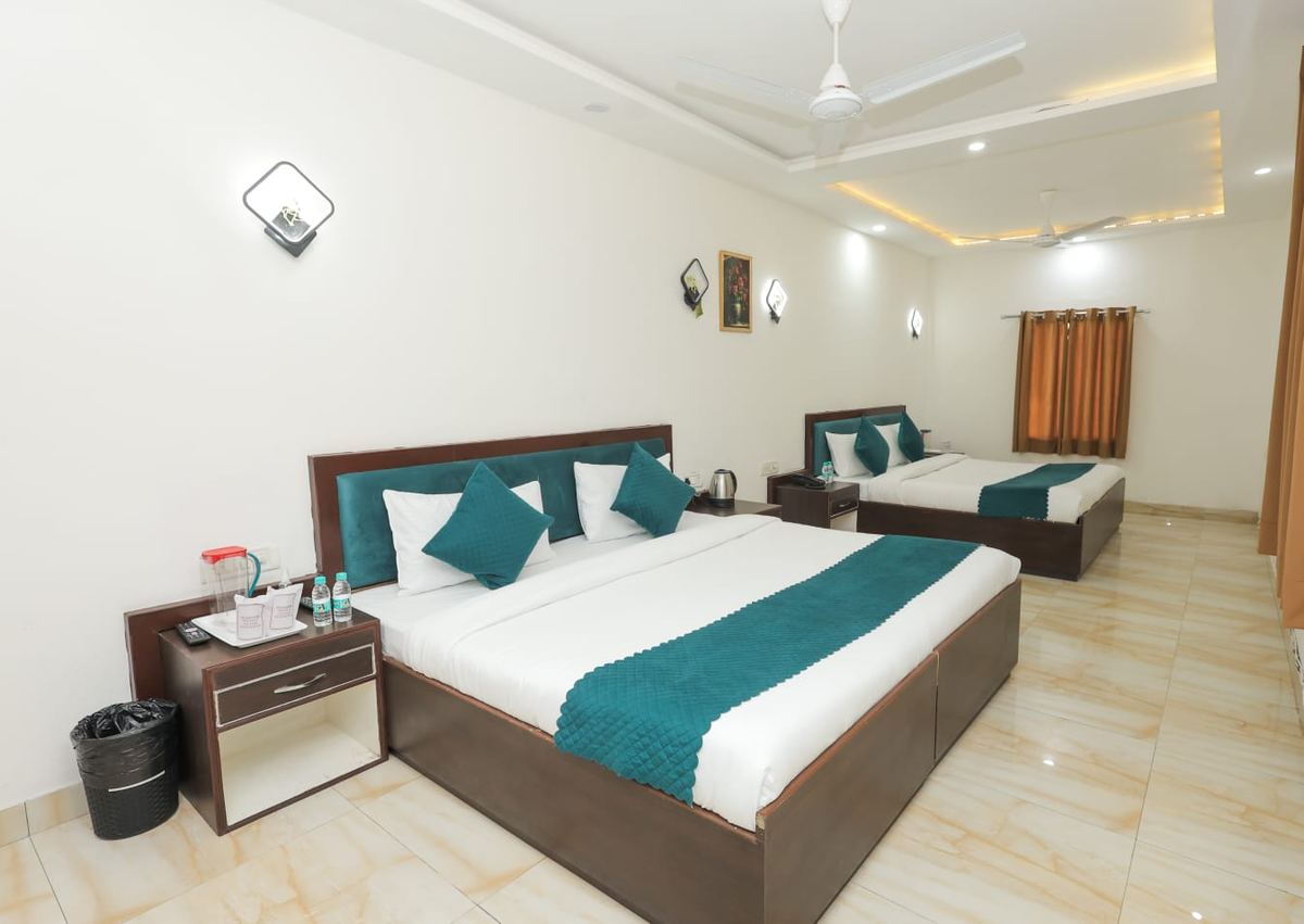 A guest room at Hotel AP Palace with two beds, teal cushions and polished tiled floor
